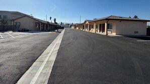 A row of single-story motel buildings with a parking lot in front. - Dutch Motel (Loma Linda)