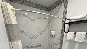 A modern bathroom with a shower, toilet, and towel rack. - Dutch Motel (Loma Linda)