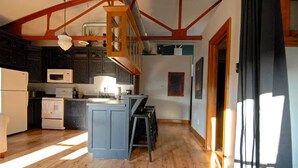 A kitchen with wooden floors, a central island, and a staircase leading to an upper level. - "Historic Loft Retreat in Downtown Bloomington" (Bloomington)