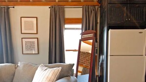 A room with a sofa, a mirror, a refrigerator, and wooden flooring. - "Historic Loft Retreat in Downtown Bloomington" (Bloomington)