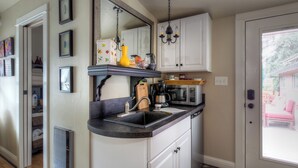 A kitchen with white cabinets, a black countertop, a built-in stove, and a microwave. - Romantic cottage with tranquil outdoor space in Willamette Valley Wine Country (Independence)