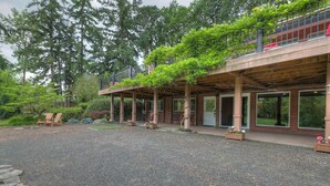A modern building with a covered patio area, outdoor seating, and a view of the surrounding forest. - Romantic cottage with tranquil outdoor space in Willamette Valley Wine Country (Independence)