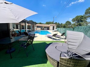 A backyard with a swimming pool, outdoor furniture, and a covered patio area. - Magnificent pool house in a green setting (Molières-sur-Cèze)