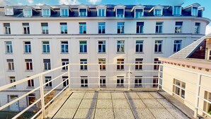 A multi-story building with a balcony area featuring a tiled floor and white railings. - Studio cosy centre avec balcon (Brussels)