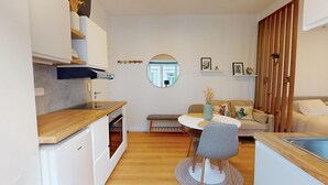 A compact living space with a kitchenette, dining area, and seating area. - Studio cosy centre avec balcon (Brussels)