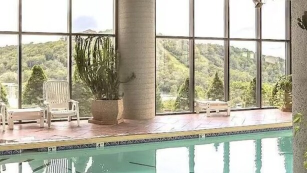 An indoor swimming pool with large windows, a potted plant, and a chair. - Charming Sky Blue 2-Bedroom Condo in Sugar Mountain with Resort Amenities (Sugar Mountain)