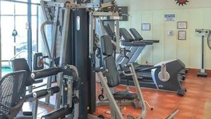 A gym with various exercise equipment, including a squat rack, bench press, and treadmills. - Charming Sky Blue 2-Bedroom Condo in Sugar Mountain with Resort Amenities (Sugar Mountain)