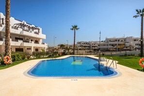 A swimming pool with a lifebuoy, palm trees, and a building with balconies. - Casa Nina (Mar de Pulpi) (San Juan de los terreros)
