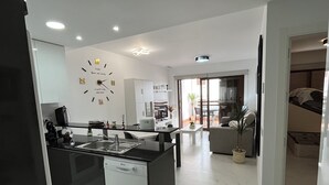 A modern kitchen with a central island, a dining area with a sofa, and a living space with a TV.