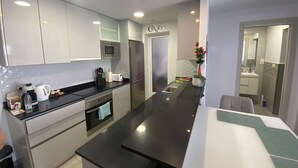 Une cuisine moderne avec des meubles blancs, des appareils en acier inoxydable et un plan de travail noir.