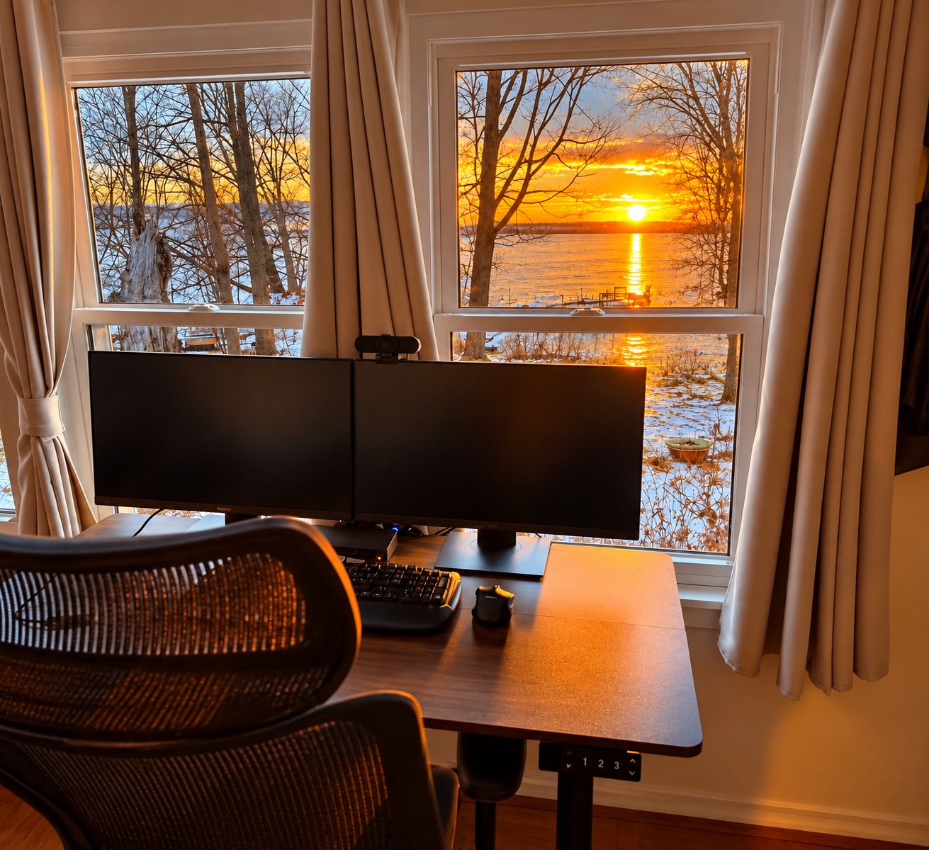 A room with a desk, two monitors, and a chair.