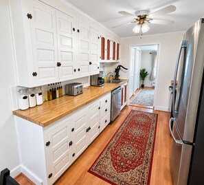A kitchen with white cabinetry, a wooden countertop, a stainless steel refrigerator, and a ceiling fan. - Lakefront Retreat. Firepit & Home Office.  Beautiful Sunsets & Great Ice Fishing (Constantia)
