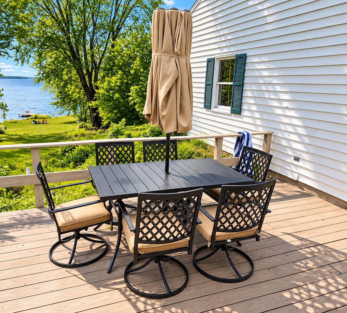 A deck with a table and chairs, a covered umbrella, and a view of a lake.