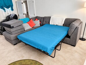 A gray sectional sofa with a blue mattress, a small ottoman, and a patterned throw blanket. - Lakefront Retreat. Firepit & Home Office.  Beautiful Sunsets & Great Ice Fishing (Constantia)