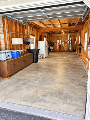 A garage with a wooden interior, a workbench, a refrigerator, and a ladder. - Lakefront Retreat. Firepit & Home Office. Beautiful Sunsets & Great Ice Fishing (Constantia)