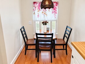 A dining area with a table and four chairs, a vase with flowers, and a window with blinds. - Lakefront Retreat. Firepit & Home Office. Beautiful Sunsets & Great Ice Fishing (Constantia)