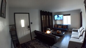 Ein Wohnzimmer mit einer Couch, einem Couchtisch, einem Fernseher und einer Treppe.