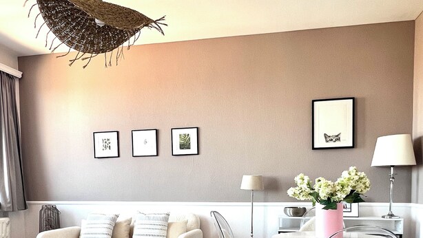 A modern living room with a sofa, coffee table, and chairs. There is a dining table with chairs, a lamp, and a vase with flowers. - Appartement Proche de l'Otan (Brussels)