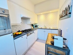 Enjoy cooking in this well-lit kitchen with a stainless steel range, compact microwave, and ample workspace.