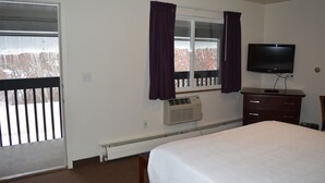 Ein Hotelzimmer mit Bett, Fernseher, Schminktisch und einem Fenster mit Vorhängen.