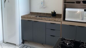 Una cocina con un refrigerador blanco, un microondas, una estufa a gas y un lavabo.