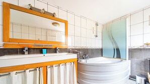 Un baño moderno con tocador de madera, un espejo grande, una bañera y una cabina de ducha de vidrio.