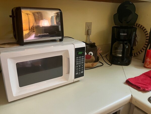 A microwave oven with a digital display, a coffee maker, and a power outlet on a countertop. - Charming 1-bedroom cottage with WiFi, AC in quaint Pilot Mountain. (Pilot Mountain)