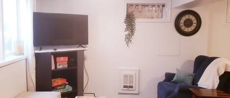 A living room with a flat-screen TV, a sofa, a coffee table, and a small bookshelf.