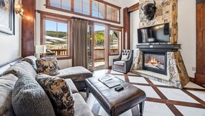 A living room with a fireplace, a television, a sofa, and a view of the outdoors.