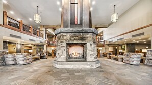 A spacious lobby with a stone fireplace, multiple seating areas, and a high ceiling with exposed beams.