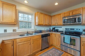 A modern kitchen with wooden cabinets, stainless steel appliances, and a window.