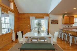 Ein Holzinterieur mit Esstisch, Stühlen, einer Bank und einer Küchenzeile mit Barhocker.