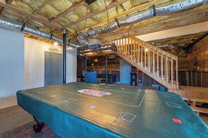 A billiards table in a room with a wooden ceiling, a staircase, and a door labeled 'Laundry'.