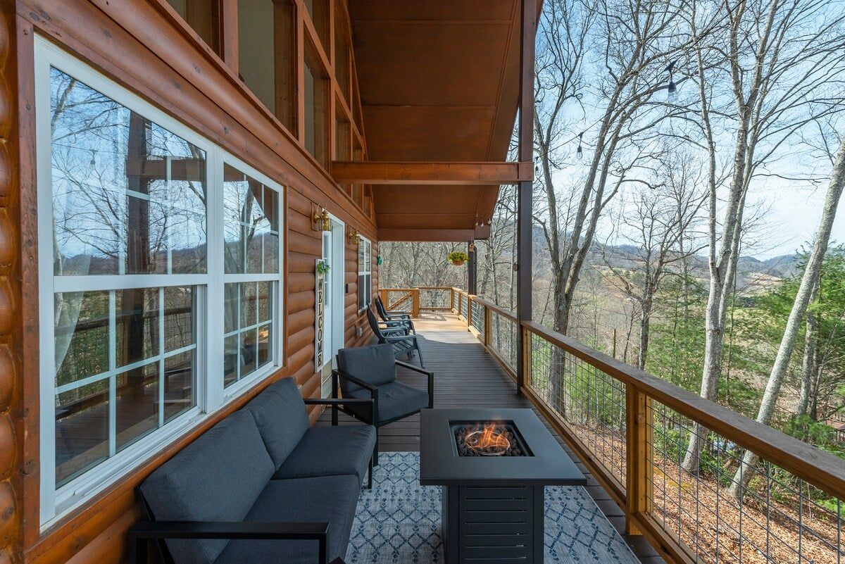 A wooden deck with a sofa and a table, overlooking a forested landscape.