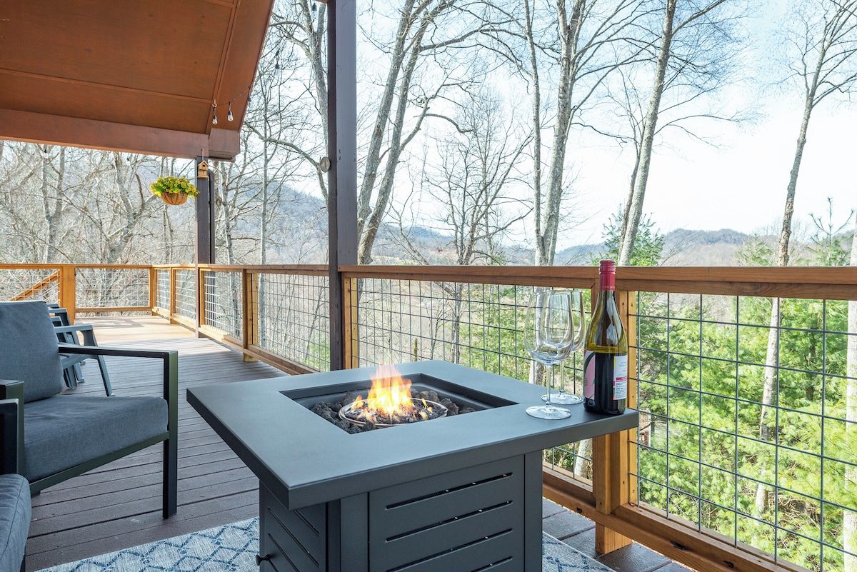 A deck with a fire feature, seating, and a wine bottle.