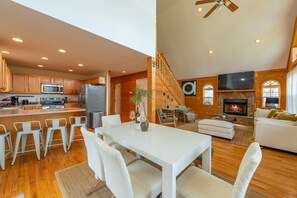A modern kitchen with a dining area, a fireplace, and a staircase leading to an upper level.