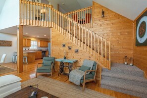 A spacious loft with a wooden staircase, a dining area, and a kitchen.
