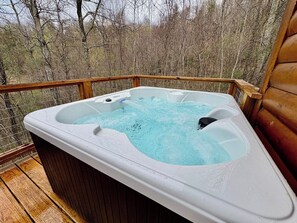 Ein Whirlpool auf einer Holzterrasse mit Blick auf Bäume.