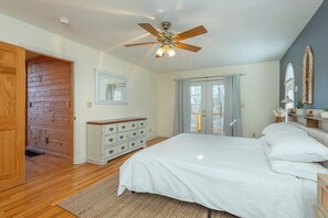 Ein Schlafzimmer mit einem Bett, einer Kommode, einem Deckenventilator und einer Tür zu einem anderen Raum.