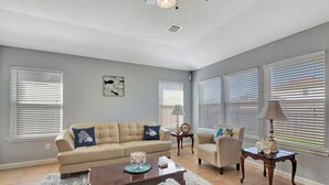 Ein geräumiges Wohnzimmer mit einem beigefarbenen Sofa, einem Couchtisch und einem Beistelltisch mit einer Lampe.