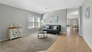 Ein geräumiges Wohnzimmer mit grauem Sofa, einem Couchtisch und einer Kommode mit Fischmotiven.