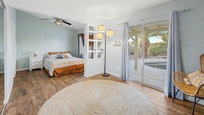 A bedroom with a bed, bedside table, lamp, floor lamp, and a view of a patio with a pool. - Charming 3-bedroom house with Pool, WiFi and AC in amazing Mesa (Mesa)