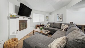 A living room with a flat-screen TV, a sofa, a coffee table, and a fireplace. - Charming 3-bedroom house with Pool, WiFi and AC in amazing Mesa (Mesa)