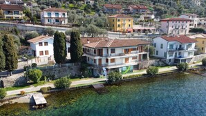 A residential area with houses along a waterfront, featuring a clear view of the water and a small dock. - VILLA ESMERALDA BETH'S HOUSE (Brenzone sul Garda)