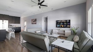 Ein modernes Wohnzimmer mit einer Couch, einem Couchtisch und einem an der Wand befestigten Fernseher.