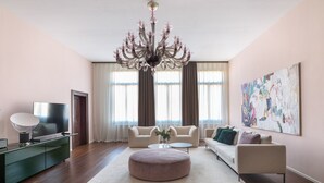 Un saló amb un candelabrum, sofàs, un televisor i obres d'art a la paret.