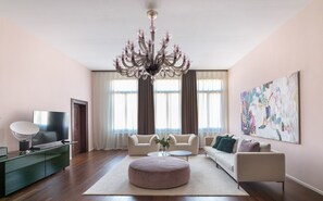 Una sala de estar con candelabro, sofás, televisor y obras de arte en la pared.