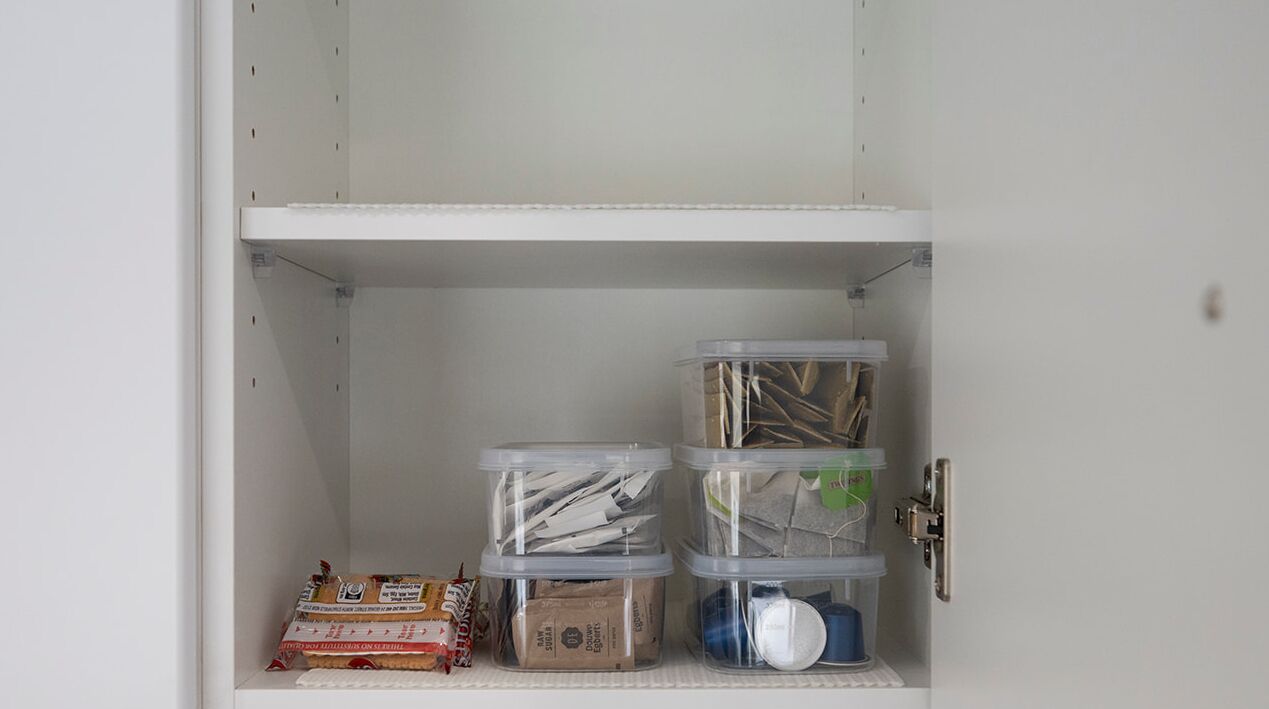 Um armário com vários recipientes de plástico transparente contendo diversos objetos.