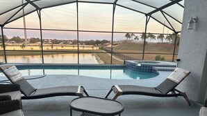 Ein überdachter Außenbereich mit Pool, Liegestühlen und einem Whirlpool.