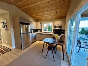 Cocina moderna con techo de madera, electrodomésticos de acero inoxidable y un ventanal con vistas al exterior.